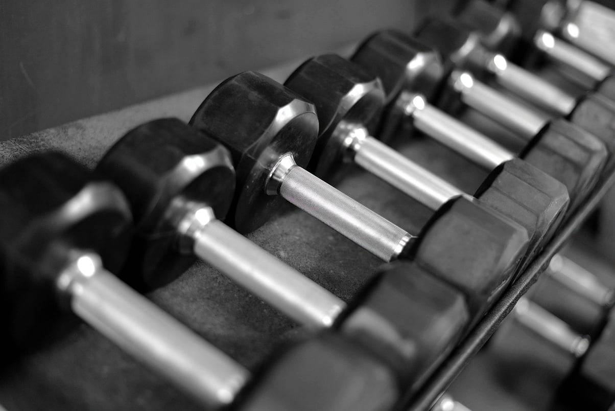 Black and white photograph of dumbells on a dumbell rack